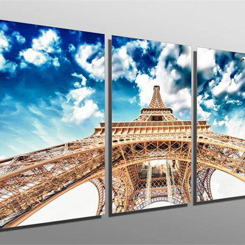 Three-panel artwork showcasing the Eiffel Tower from a low-angle perspective against a partly cloudy blue sky, ideal for custom framing.