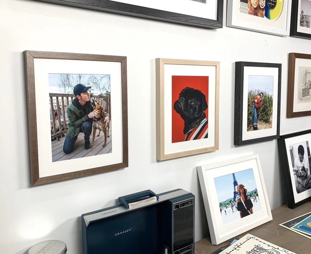 A wall showcases several beautifully framed photos, including a man with a dog, a black dog on a red background, and people posed outdoors. Below, a vintage radio sits on the shelf, offering charming gift ideas for those who cherish nostalgia.